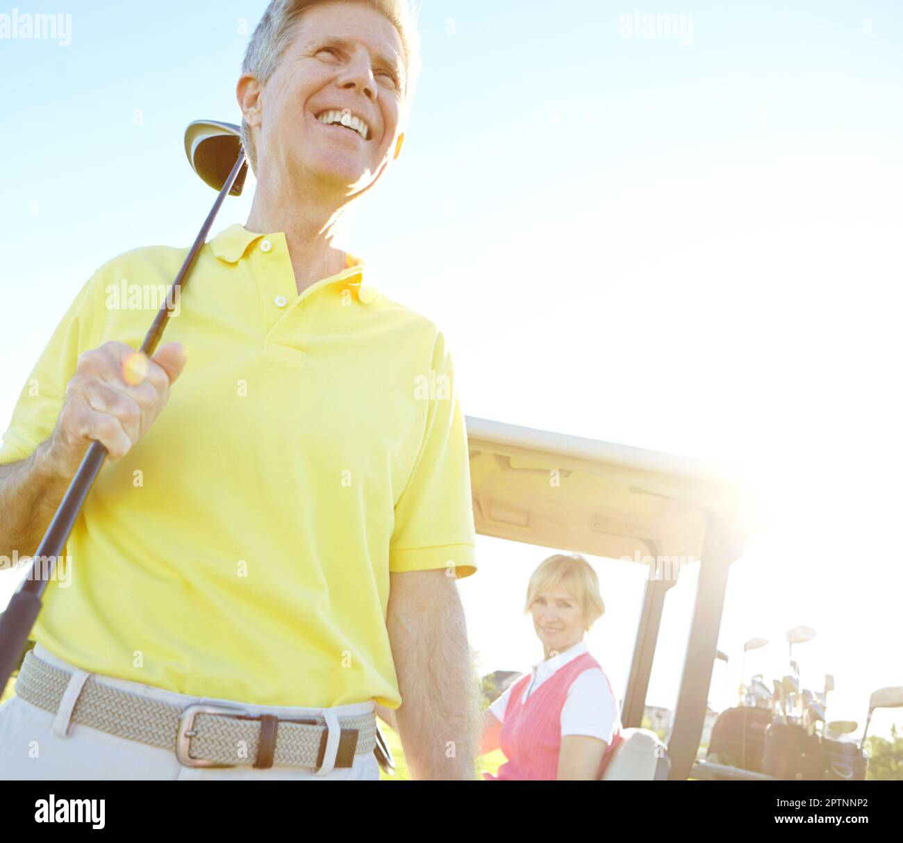 Lazy afternoon of golf. Low angle shot of a handsome older golfer standing in front of a golf cart with his golfing buddy behind the wheel. Stock Photo
