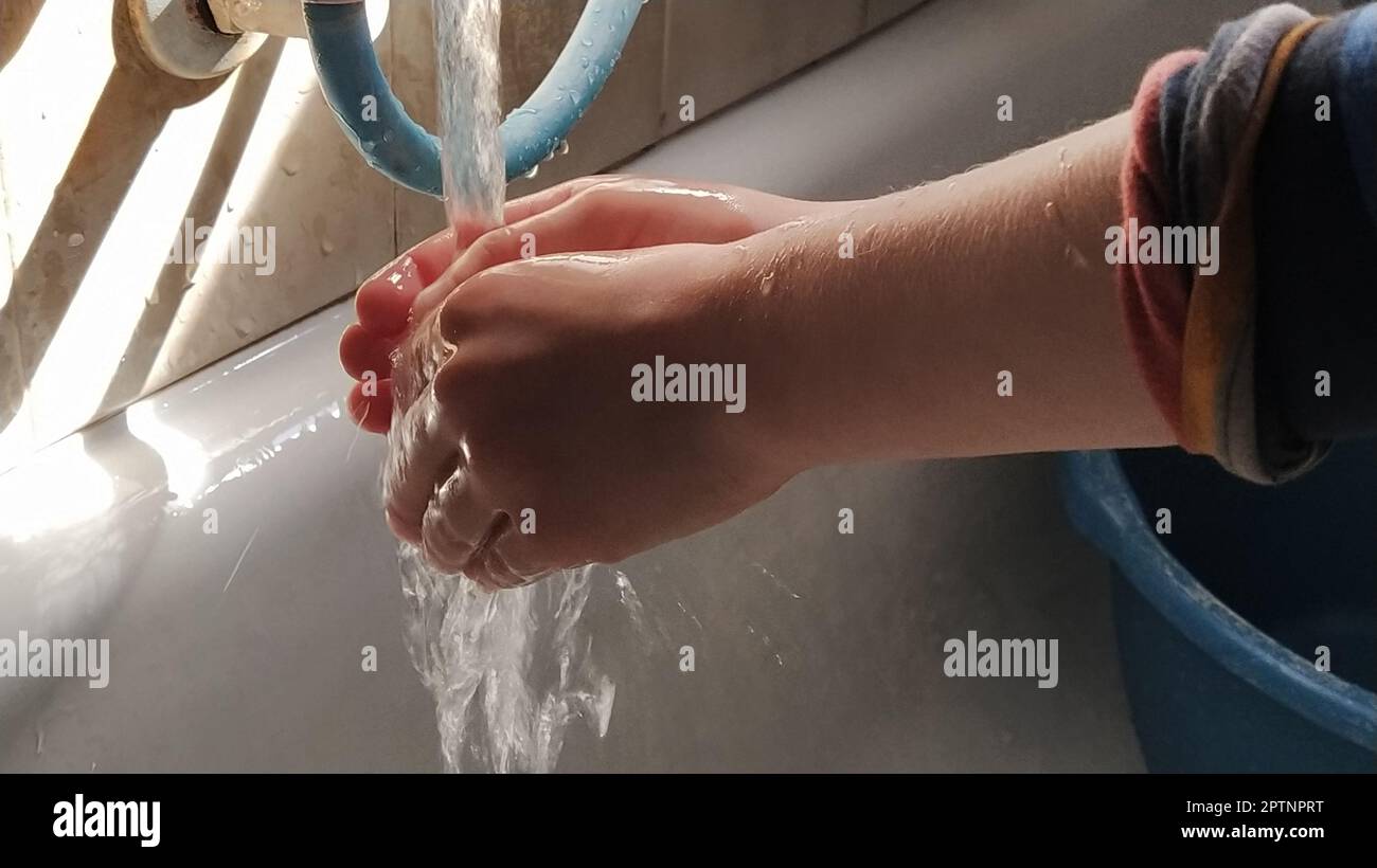 Washing hands with warm water at home over the bathtub and basin. Children's hands. Water flows