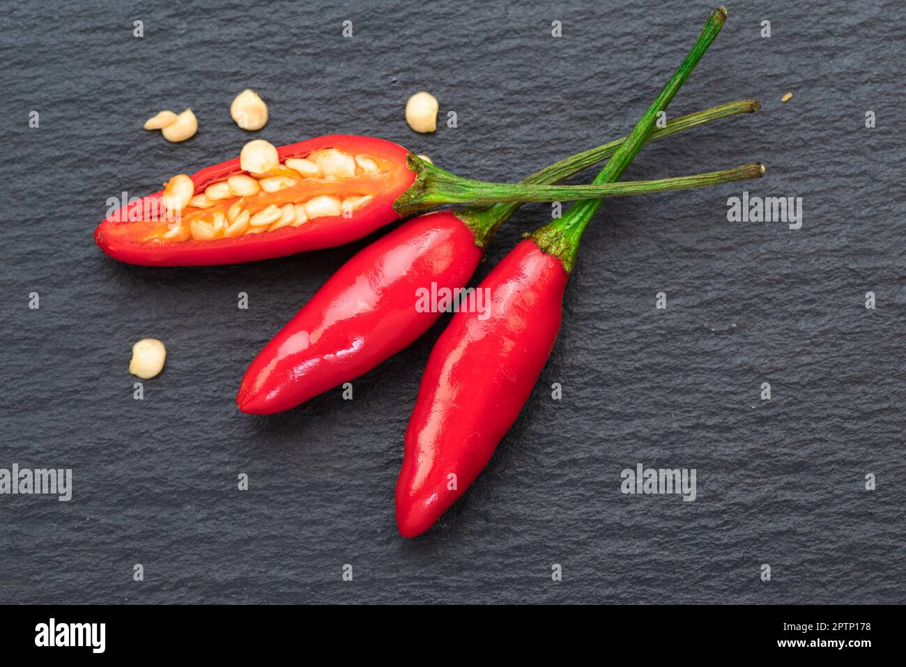 Chilli pepper or hot red peppers on natural stone black slate plate. Flat lay. Stock Photo