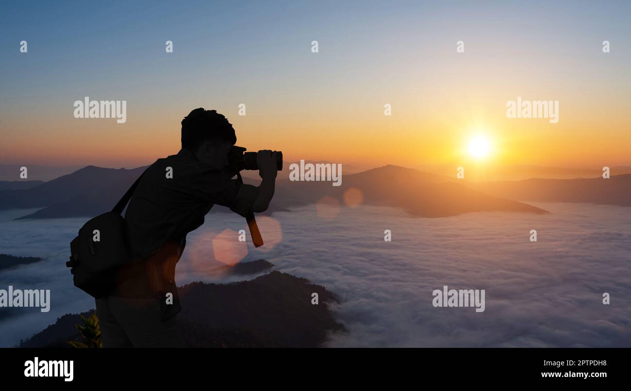 Silhouette of male photographer taking picture against sunset sky background. Stock Photo