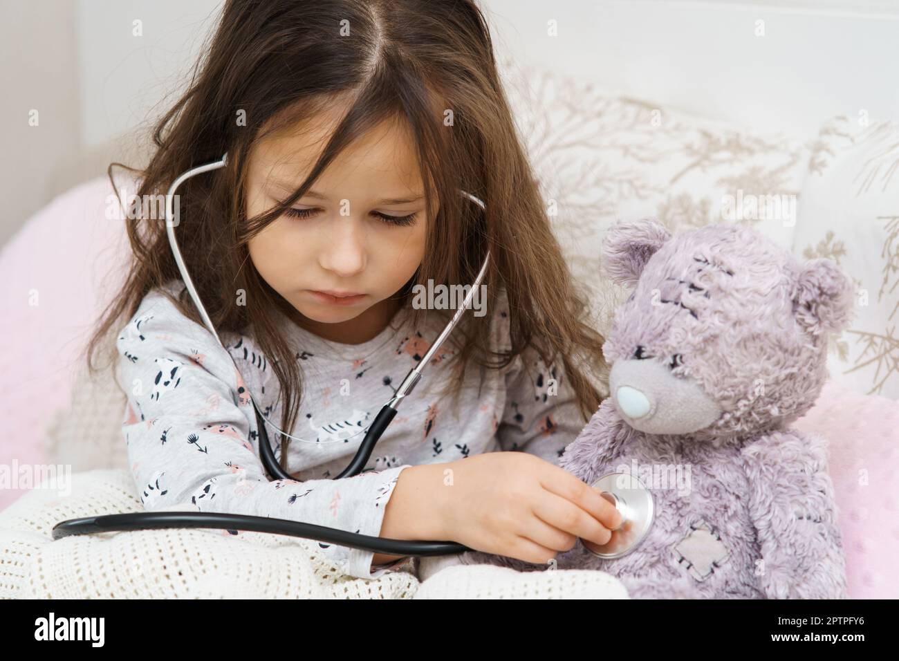 Serious, concentrated, careful small child, girl checking teddy bear
