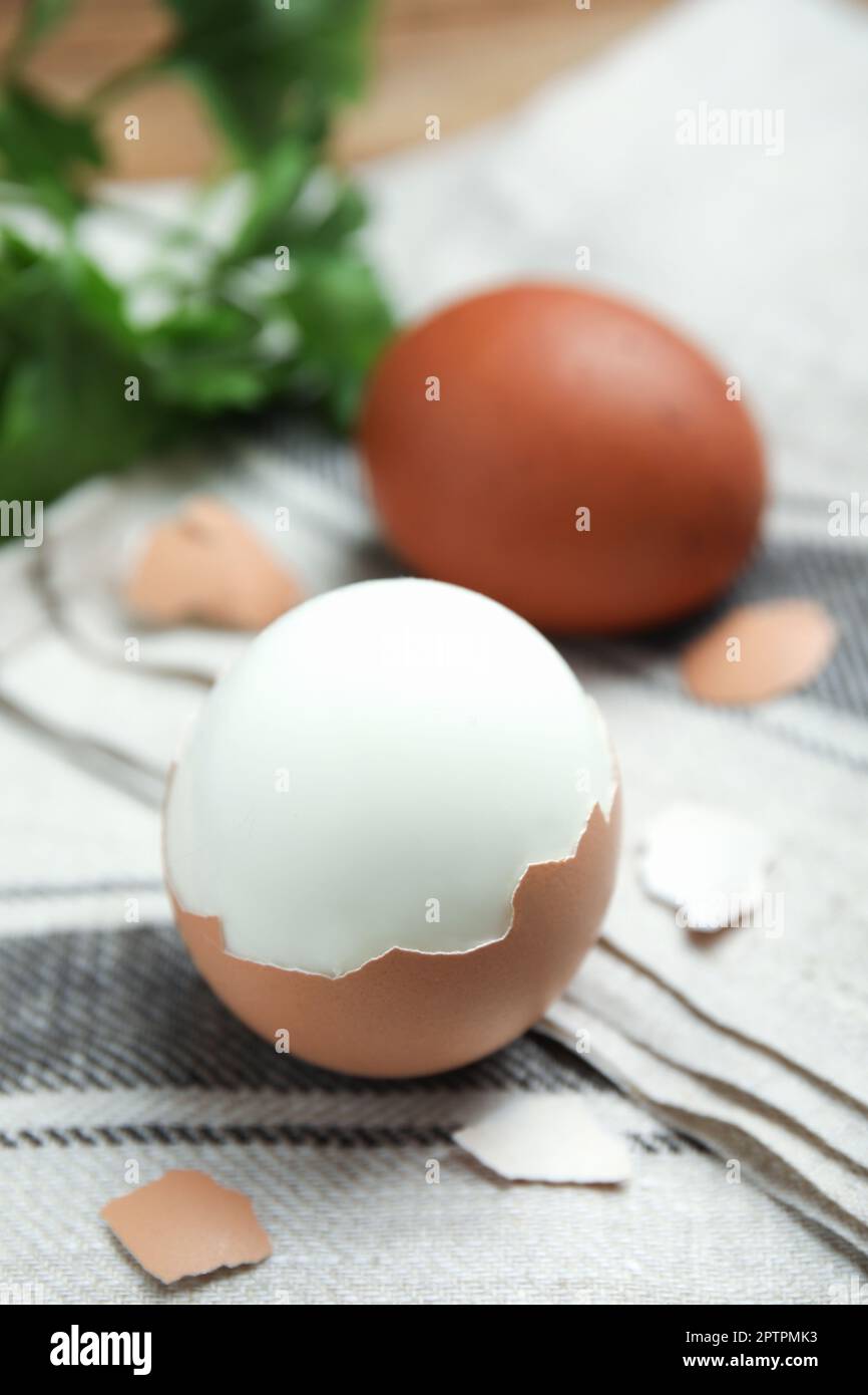 Boiled eggs and pieces of shell on kitchen towel, closeup Stock Photo