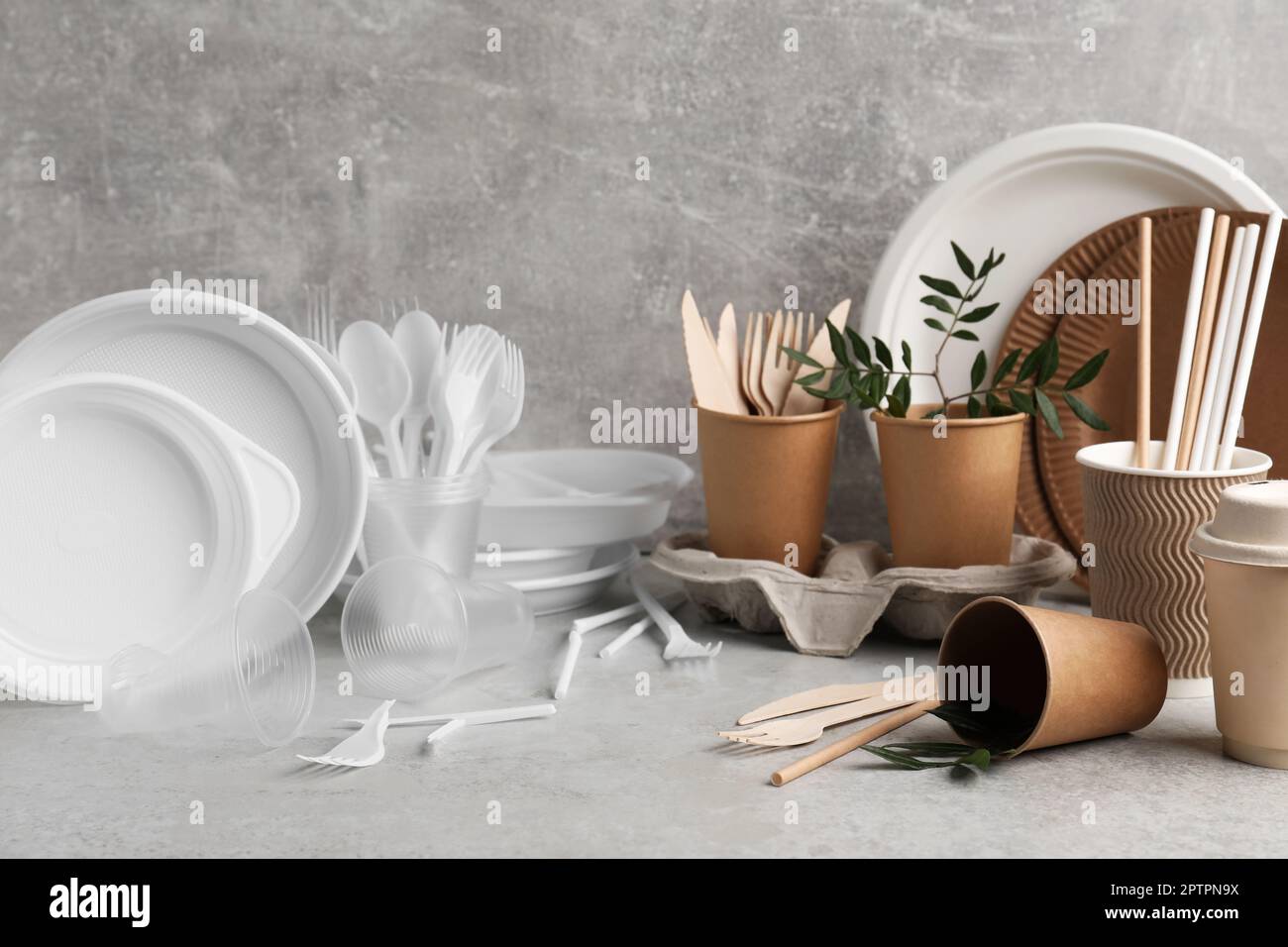 Plastic and eco disposable tableware with green twigs on marble table Stock Photo
