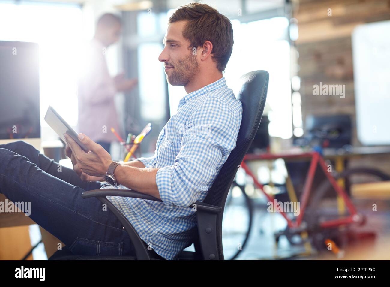 Hes making some progress on his new project. a designer using a digital tablet while working in an office. Stock Photo