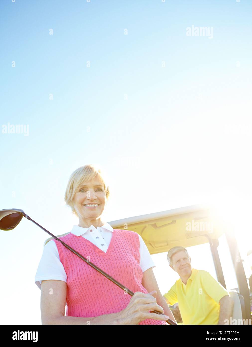 Teeing off at tea time. Low angle shot of an attractive older female golfer standing in front of a golf cart with her golfing buddy behind the wheel. Stock Photo