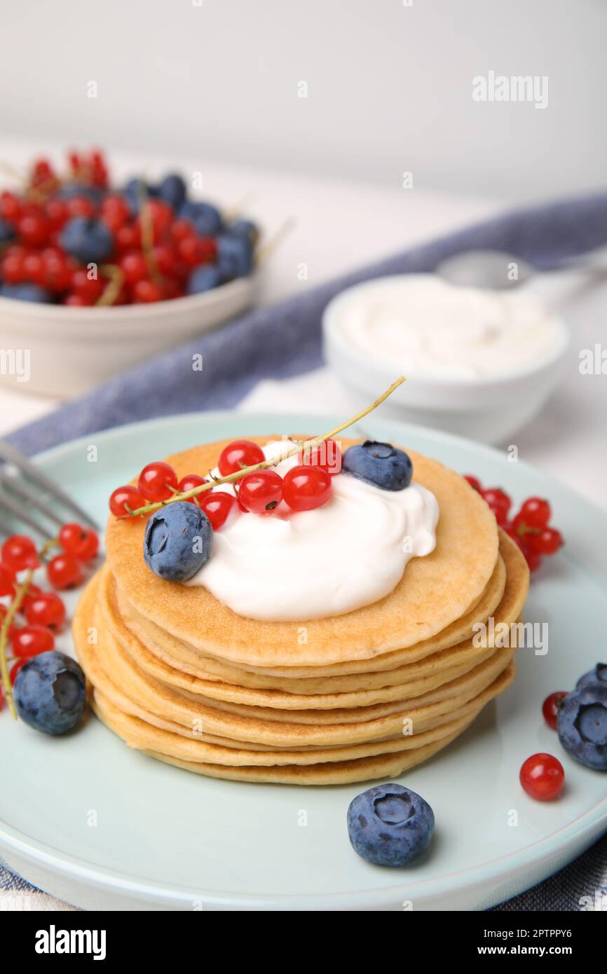 Tasty pancakes with natural yogurt, blueberries and red currants on table. Space for text Stock Photo