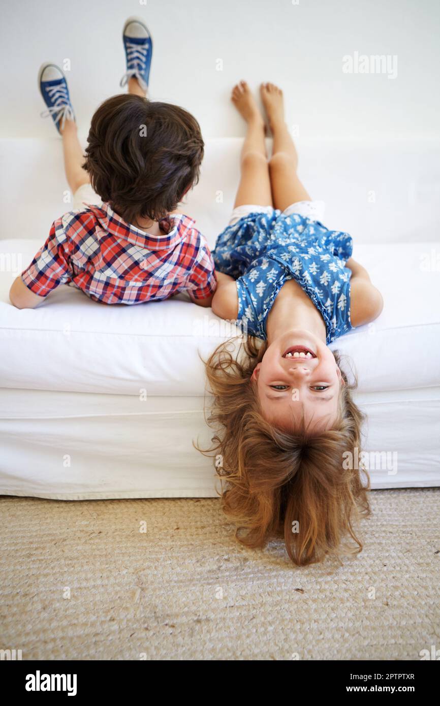 Hanging out with my brother. a young brother and sister playfully hanging  upside down on the edge of the sofa Stock Photo - Alamy