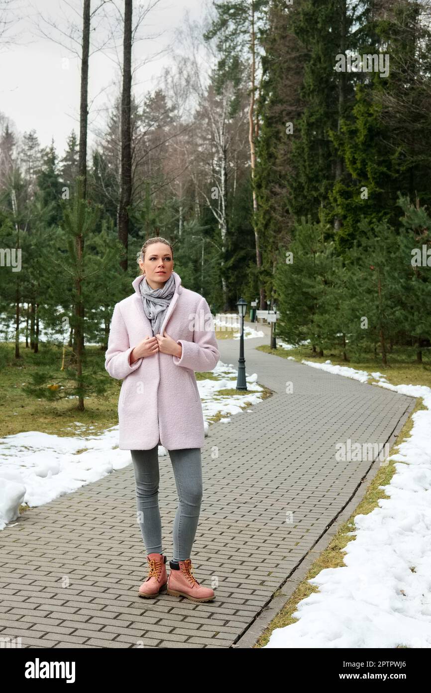 Pretty girl in pink coat walking along pathway in forest Stock Photo