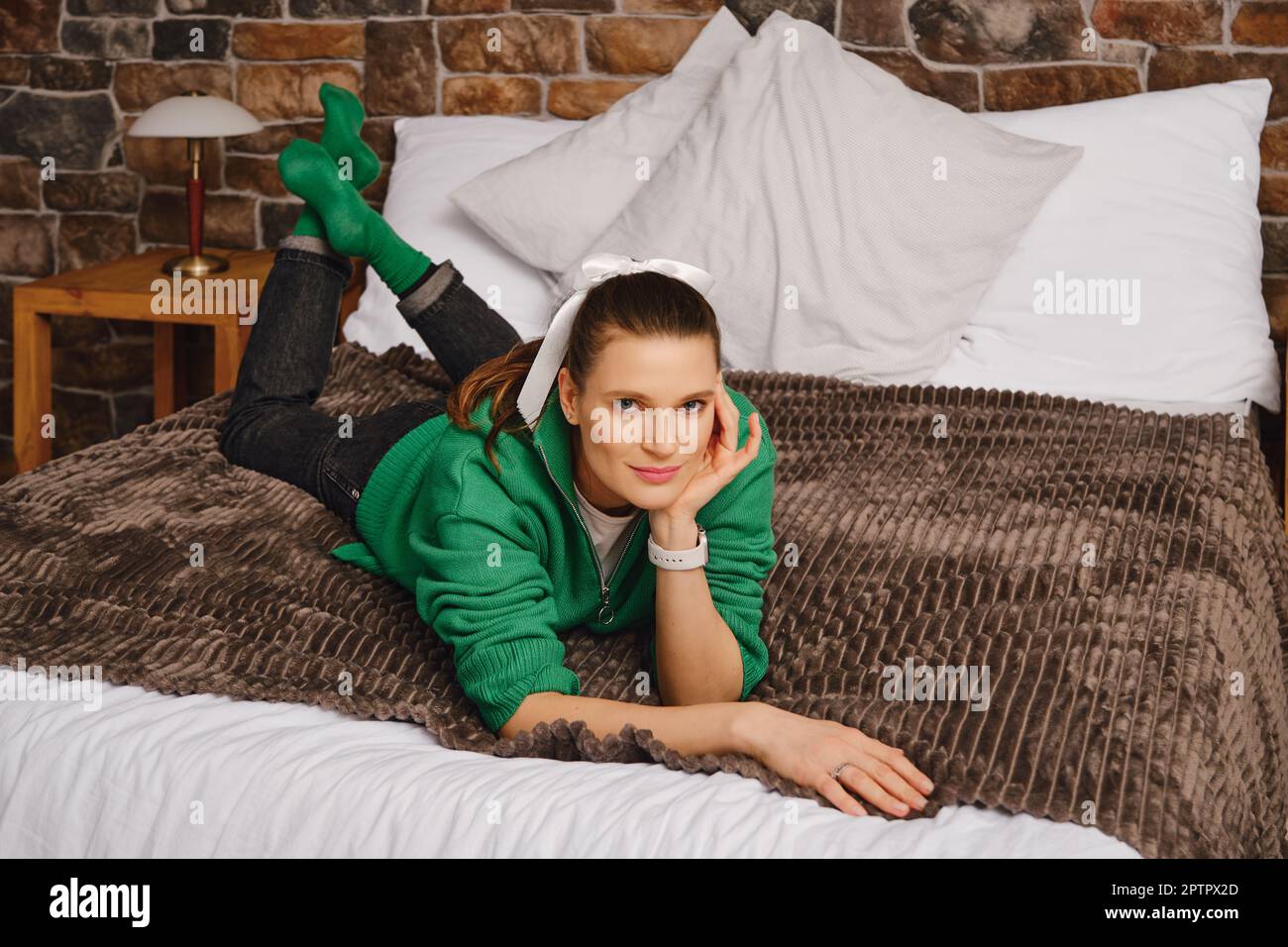 Smiling and positive woman lying on bed in her bedroom propping her