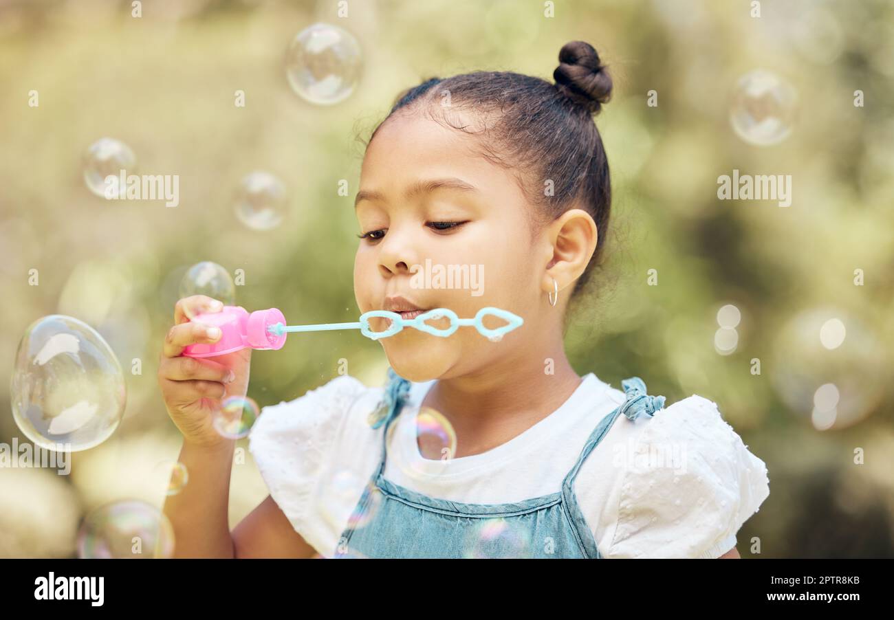 Tiny bubbles. a little girl blowing bubbles in a garden at home Stock