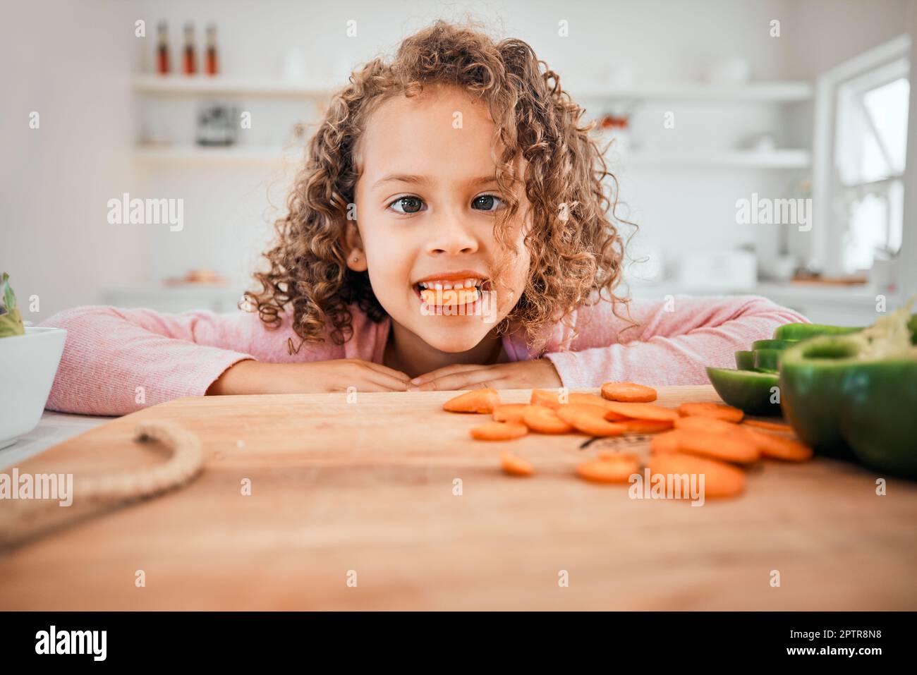 Keeping my vision clear. a little girl eating carrots at home Stock
