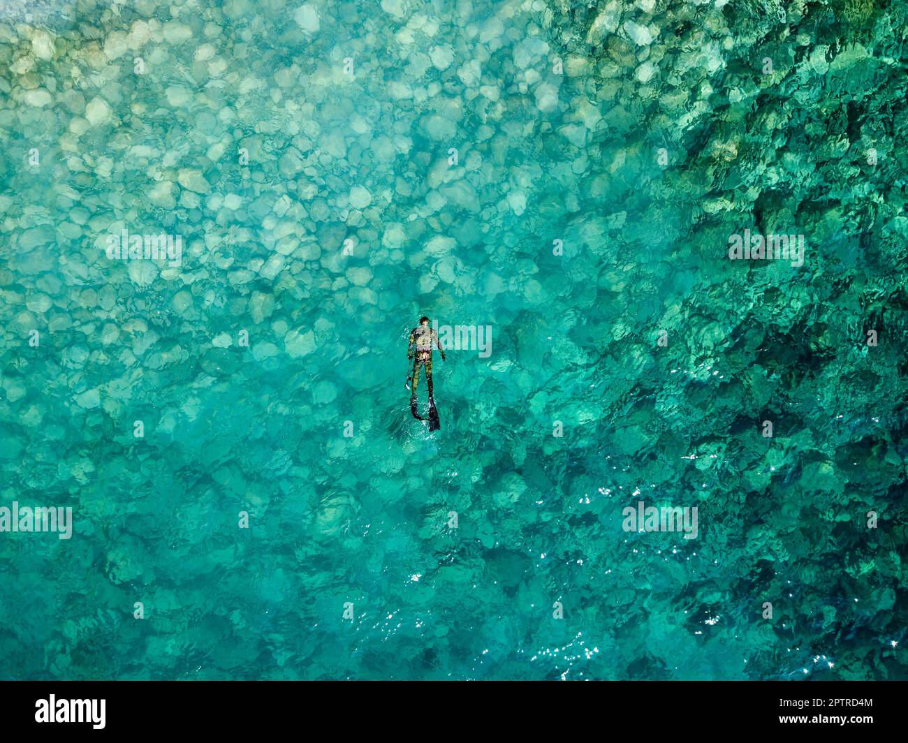 Aerial drone view of a person doing spearfishing on crystal blue water
