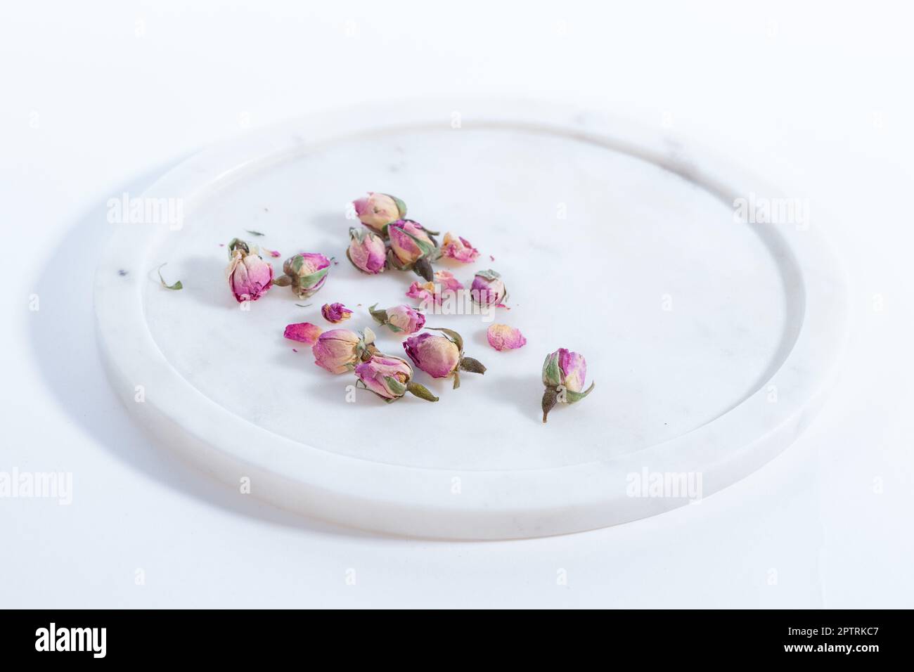 beautiful and pink small dried roses on a on a marble plate white background Stock Photo