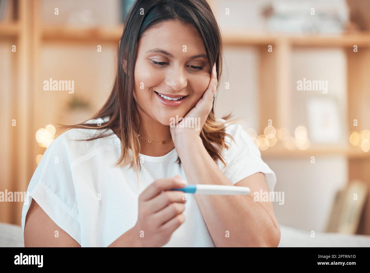 Wow, pregnancy test results and indian woman on sofa of living room at home with happy surprise