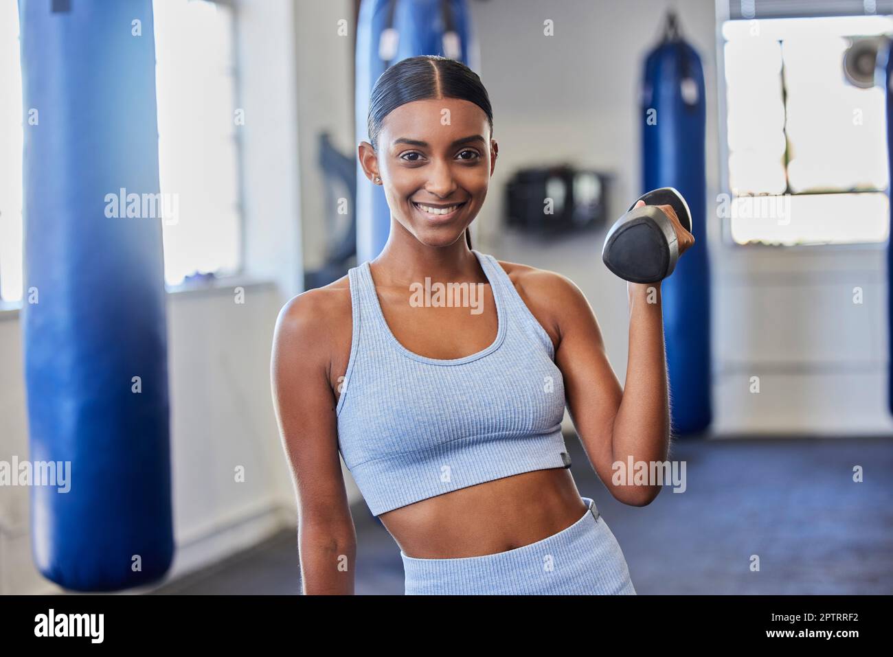 Happy woman, fitness and dumbbell exercise in gym for strong body