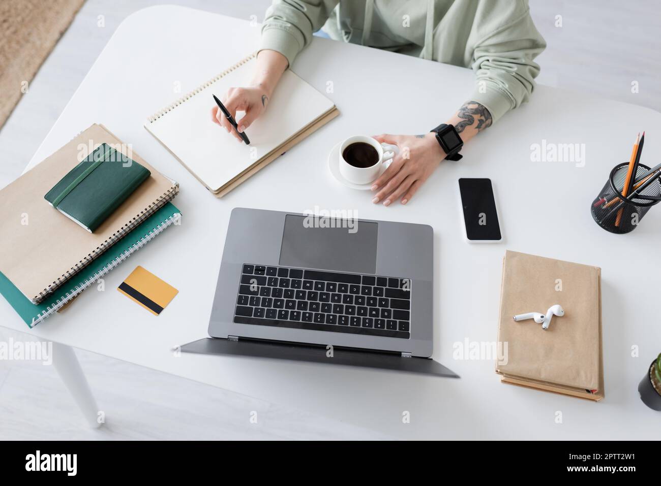 Top view of tattooed freelancer sitting near coffee and devices on table at home,stock image Stock Photo