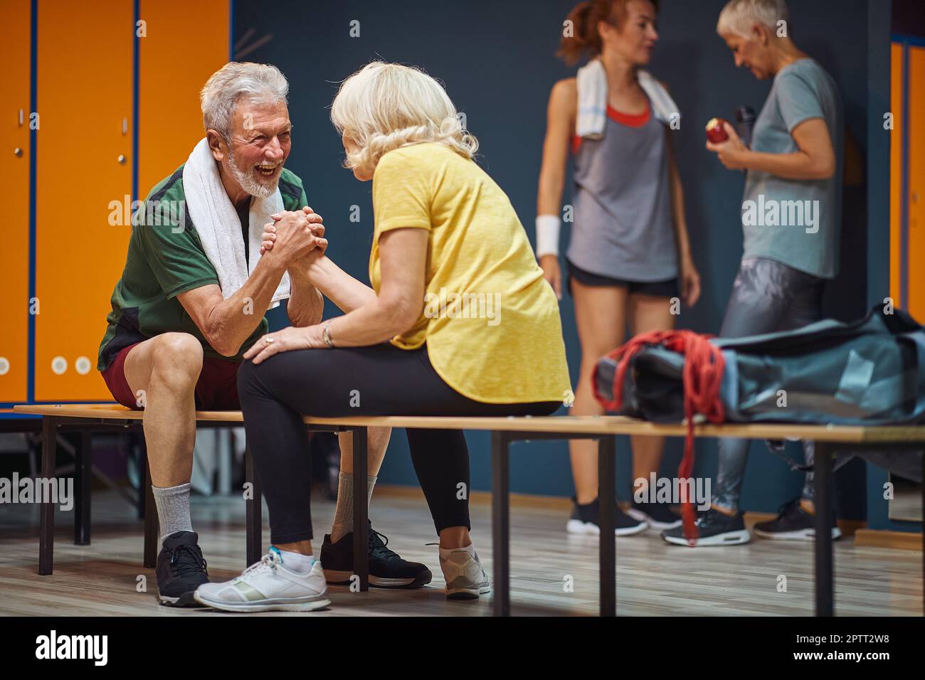 Senior man and woman arm wrestling and having fun in gym locker room. Health, wellness, active lifestyle concept. Stock Photo