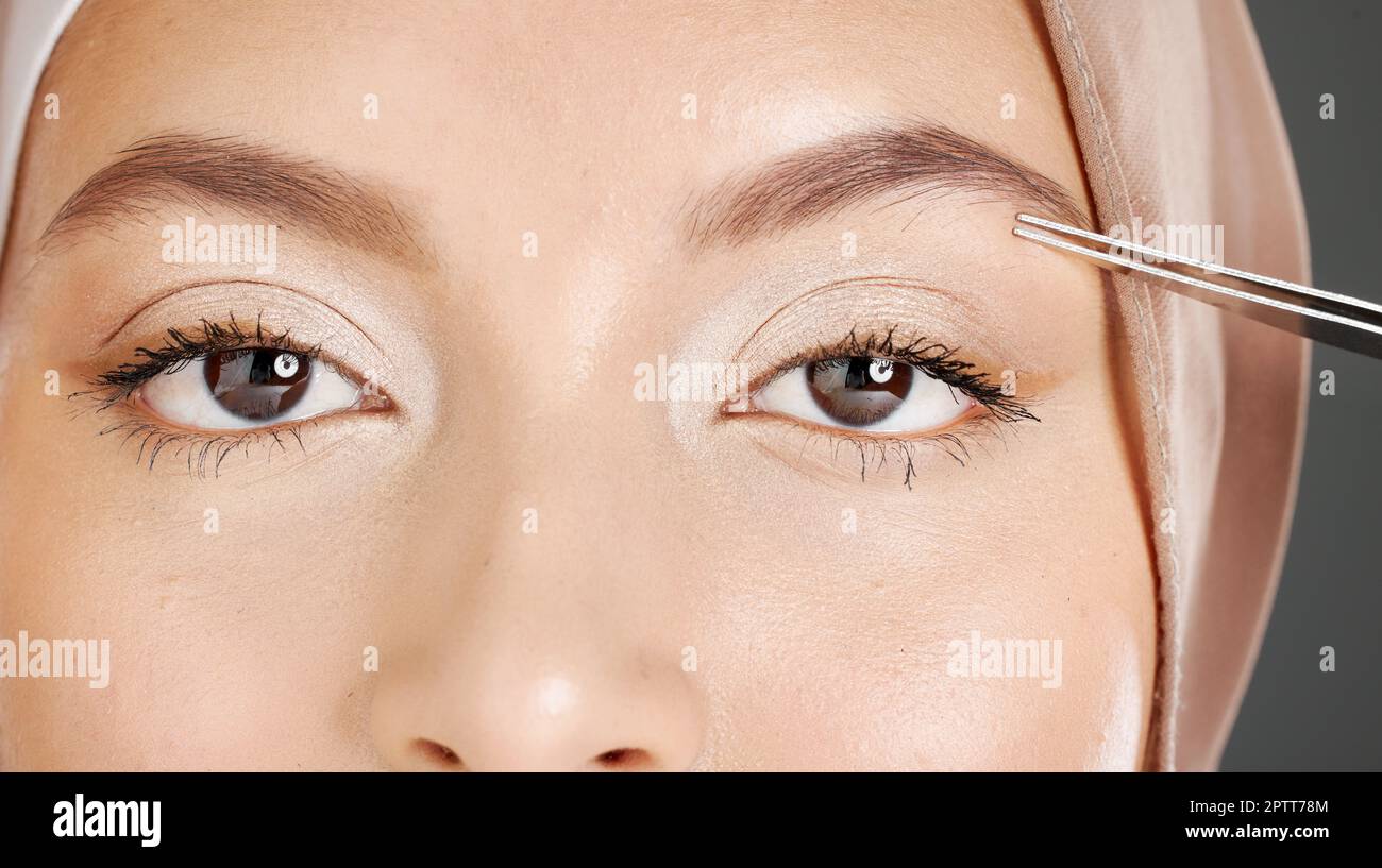 Closeup portrait of traditional muslim woman using tweezers to pluck