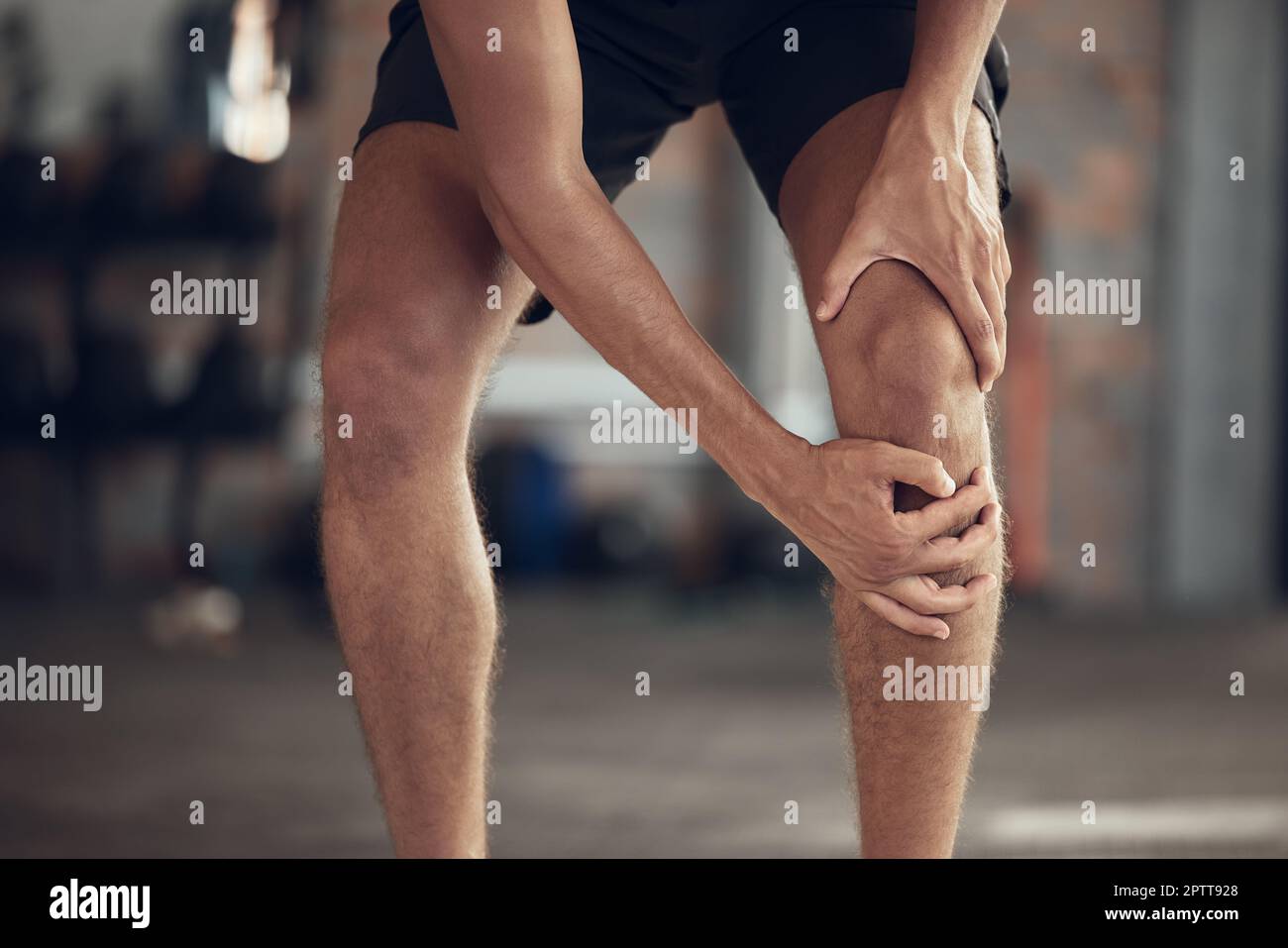 Closeup of athlete knee joint pain. Hands of fit man touching his knee