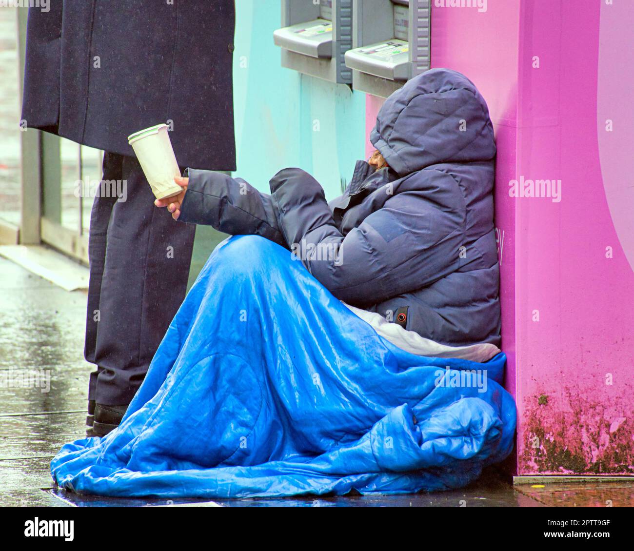 Glasgow, Scotland, UK 28th , April, 2023. UK Weather:Rain in the city’s style mile the shopping capital of scotland Buchanan street as a begger tries his luck beside a cash machine. Credit Gerard Ferry/Alamy Live News Stock Photo