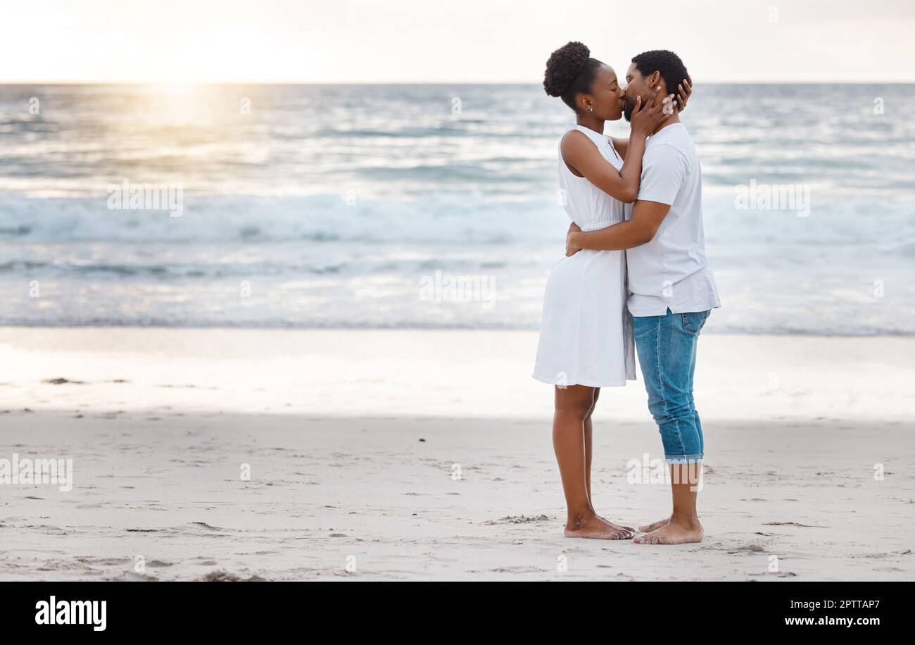 Fullbody of a happy african American couple spending a day at the sea  together. Content boyfriend and girlfriend kissing lovingly on the beach.  Caring Stock Photo - Alamy