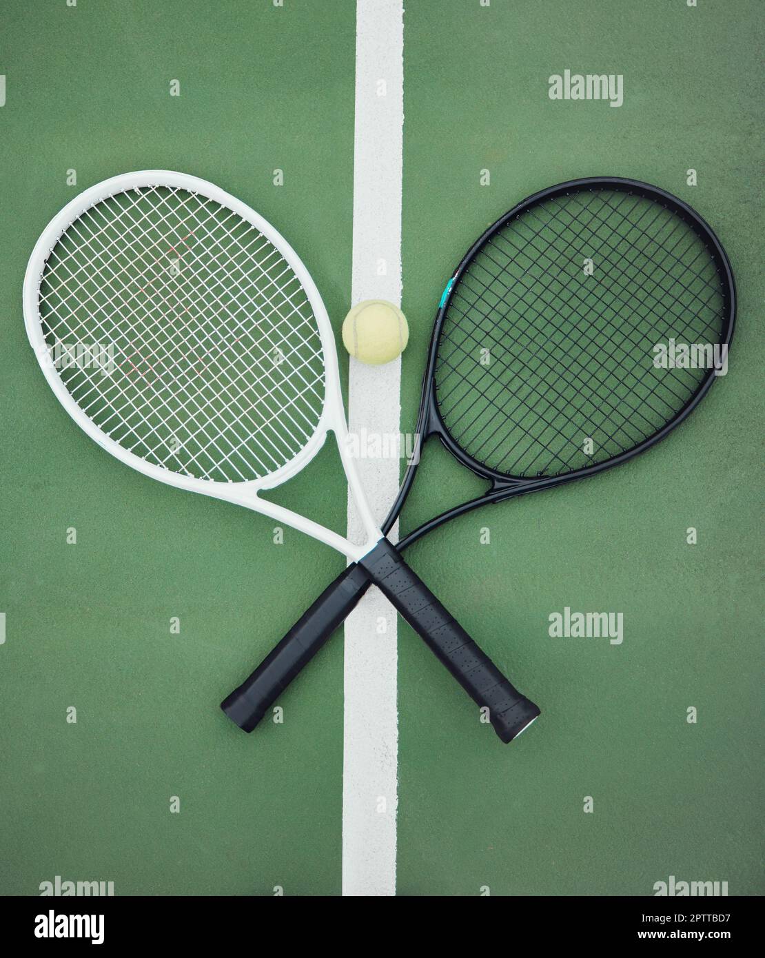 Above view of two tennis rackets and a ball on an empty court in a