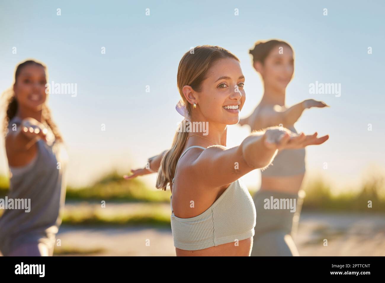 Diverse smiling yoga women in warrior pose during outdoor practice in remote nature. Group of happy active friends bonding and balancing while stretch Stock Photo