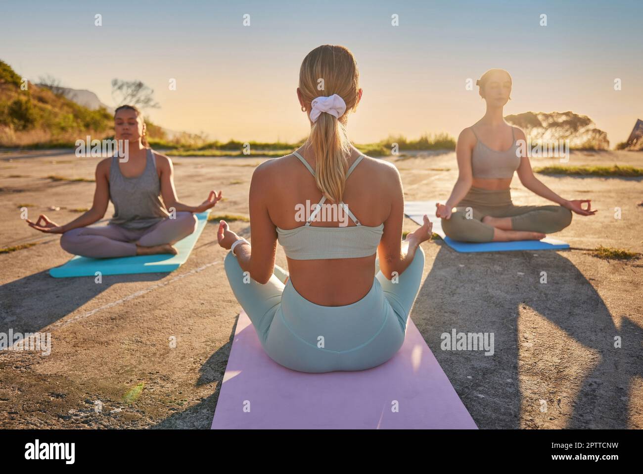Full length yoga women meditating with legs crossed for outdoor practice in remote nature. Diverse group of mindful active friends bonding and balanci Stock Photo