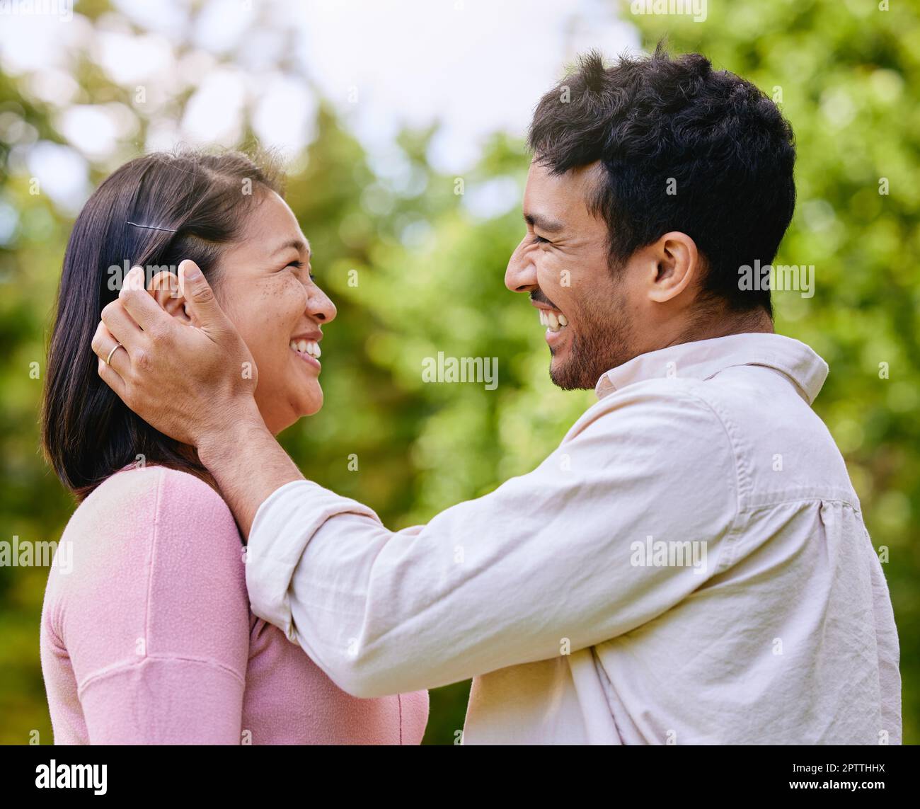 Loving husband putting hair behind wifes ear standing face to face in a  park. Happy romantic moments of lovely couple spending time together  outdoors Stock Photo - Alamy