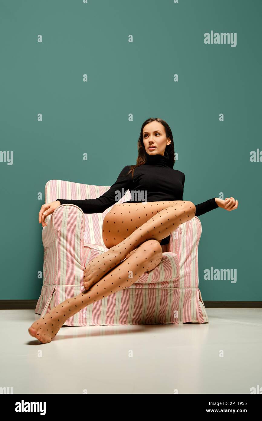 Beautiful mixed race woman in tights with polka dot pattern sits in an  armchair Stock Photo - Alamy