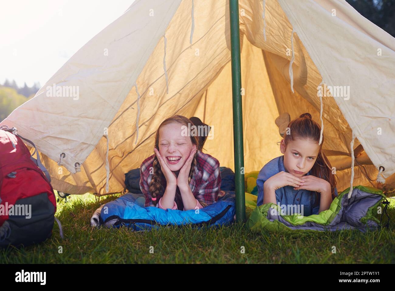 Girls only tent, no boys allowed. Two young girls lying on their sleeping bags in their tent Stock Photo