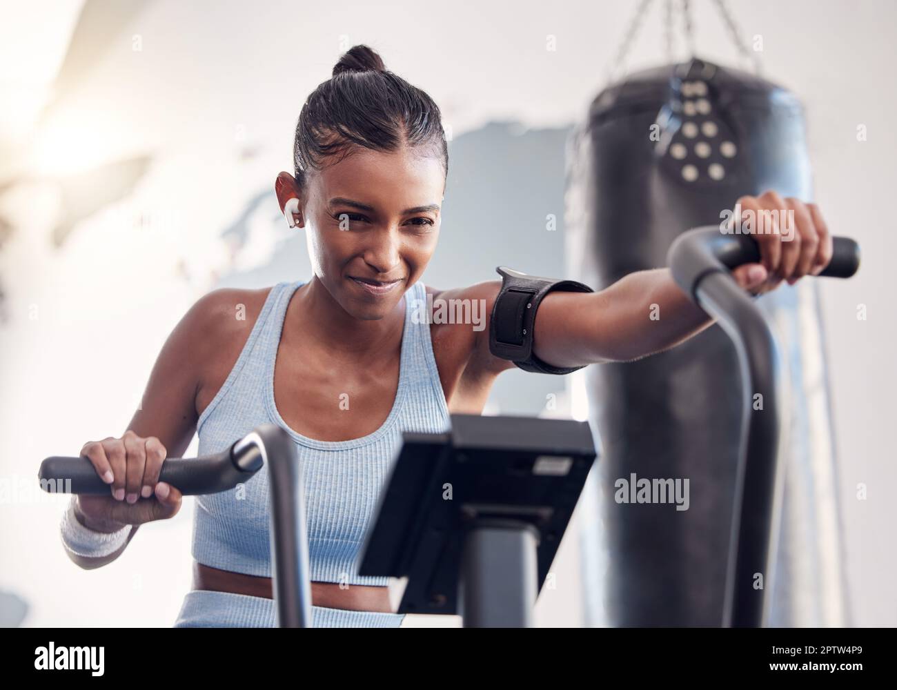 Full body strong sportswoman hanging on gymnastic rings and swinging while  exercising during intense training in dark gym stock photo