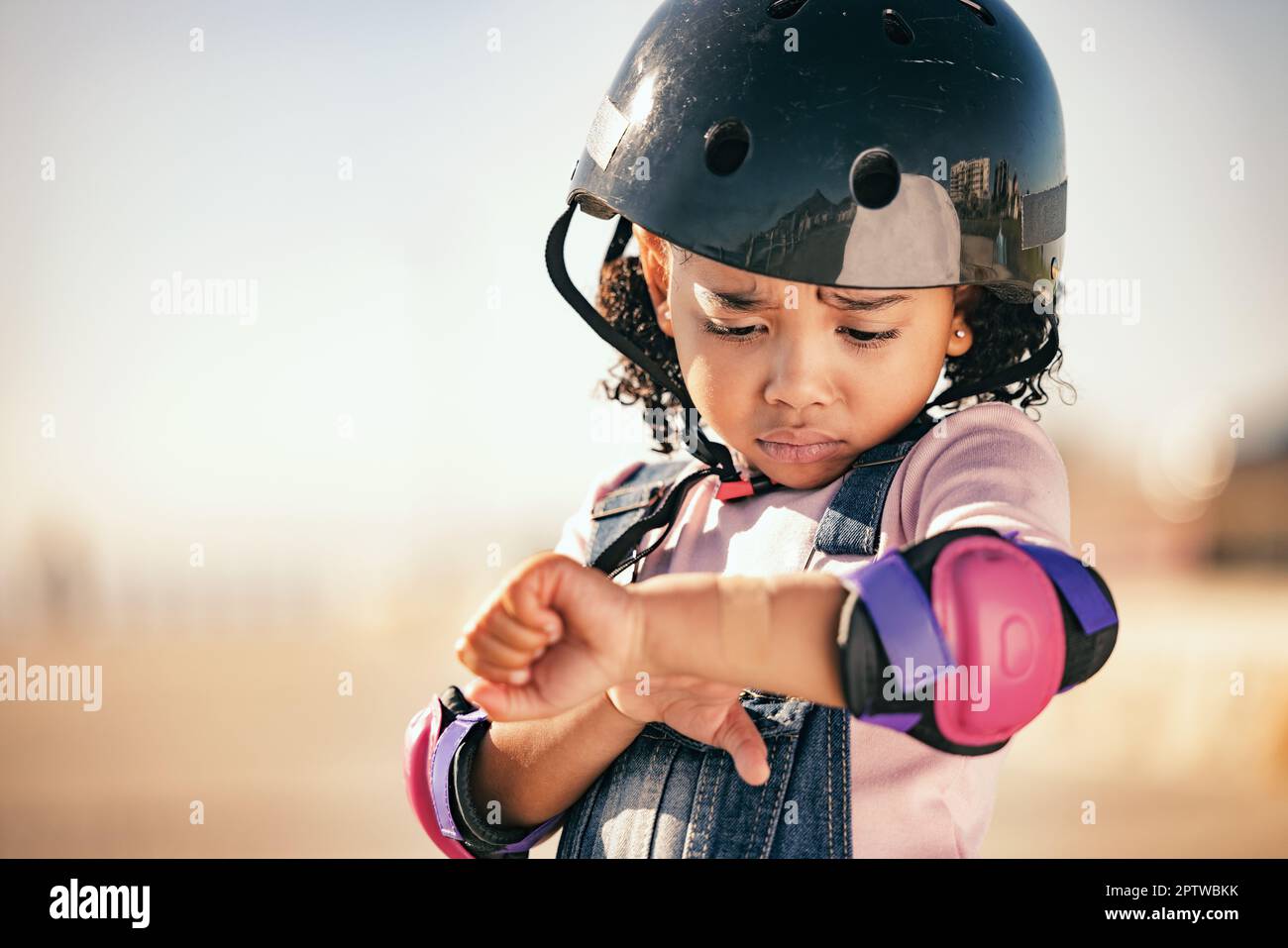 Cycling injury, child and pain from a bike accident outdoor feeling stress and sadness. Young girl and summer cyclist or skating activity with a helme Stock Photo