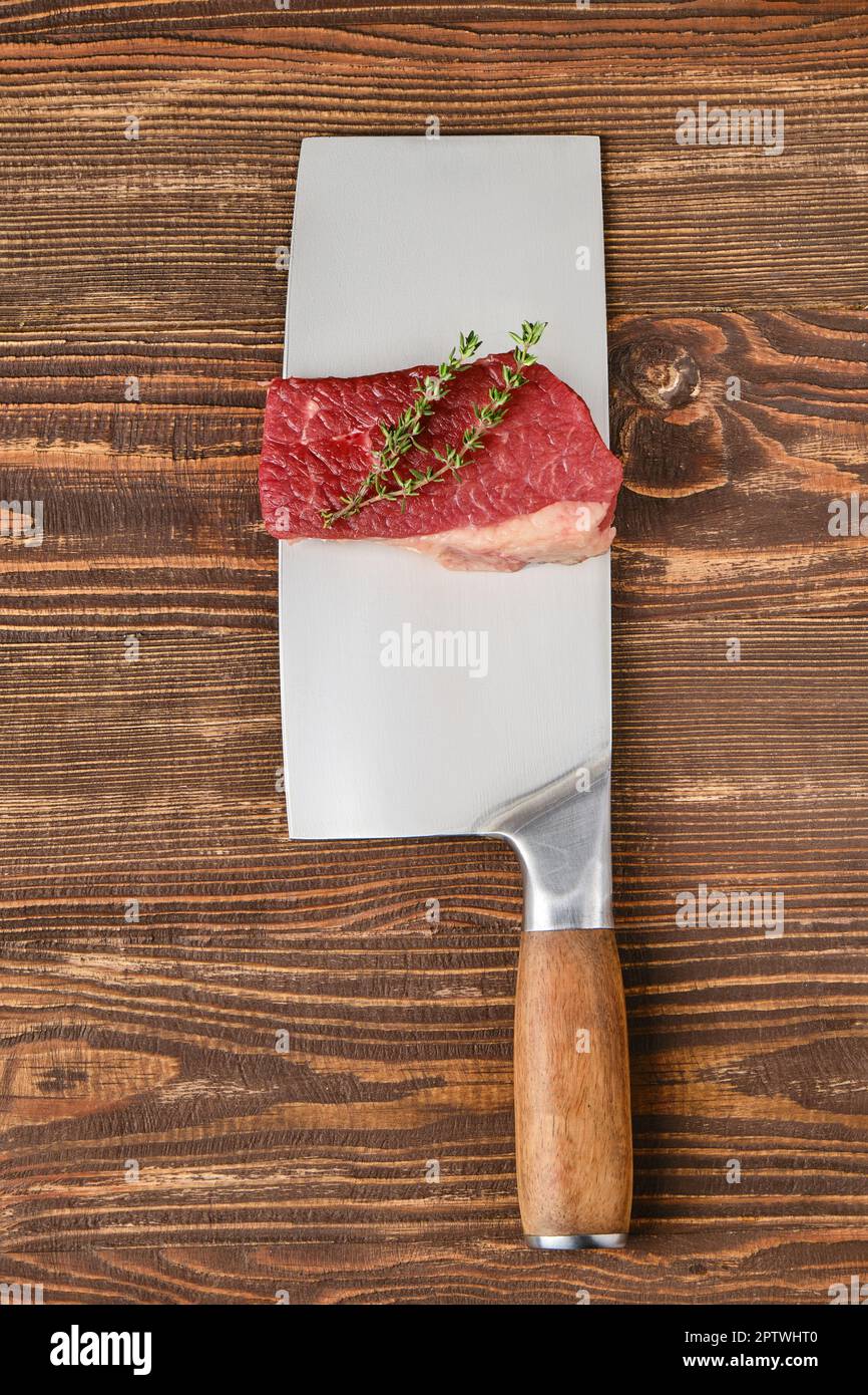 Piece of raw beef eye of round steak on butcher's cleaver with place