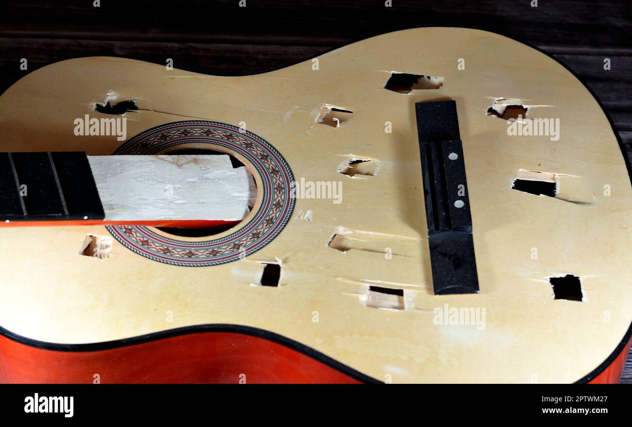 A broken wooden old classic guitar with damaged strings chords