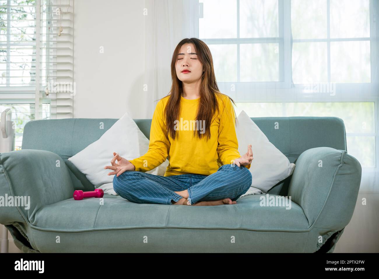 Asian young woman sits on sofa at home and chilling with couch lotus
