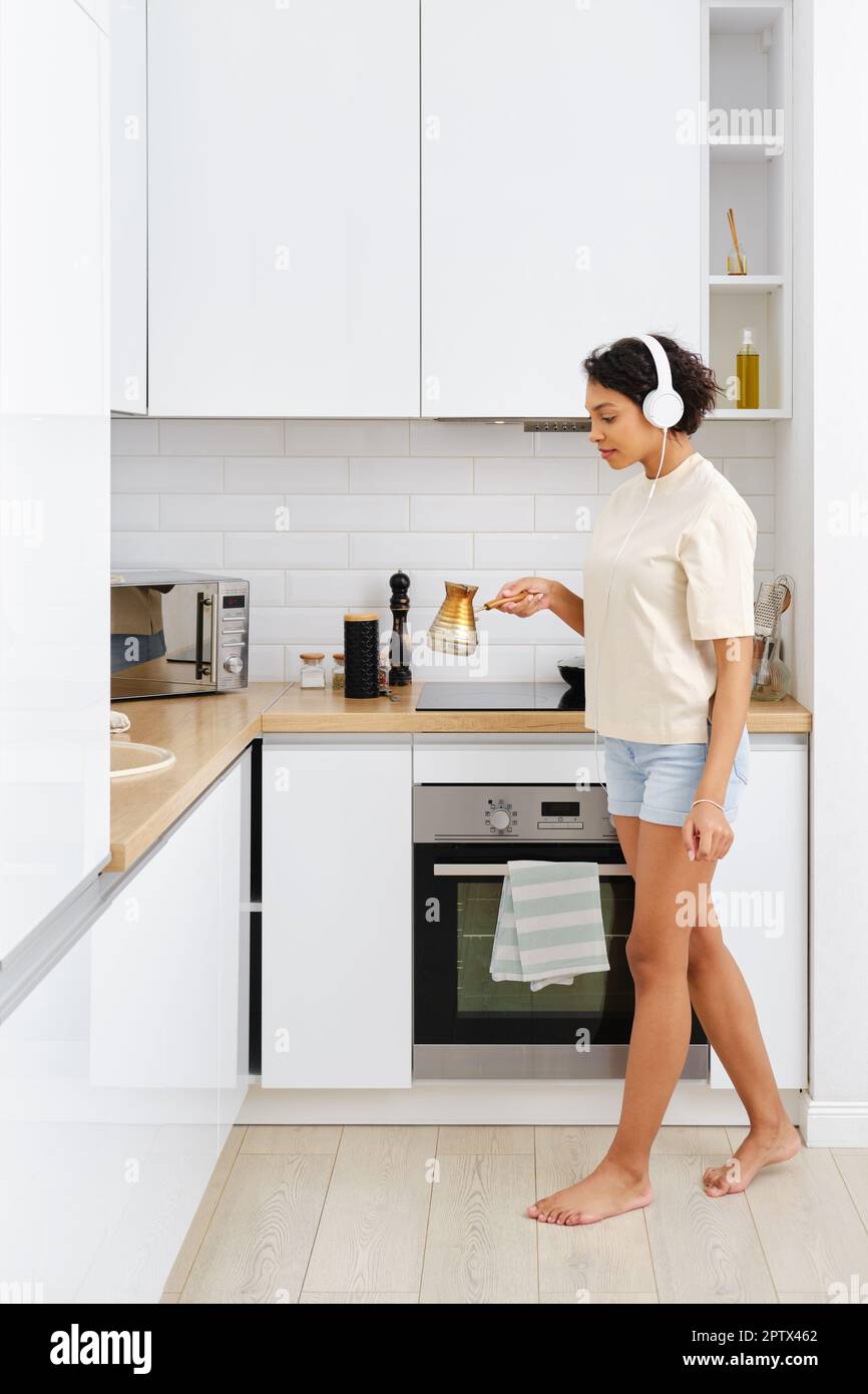 Young beautiful girl in panties and t-shirt listening to music in the  kitchen and cooking. Young female with headphones on the kitchen. Stock  Photo by ©flowertiare 153509830