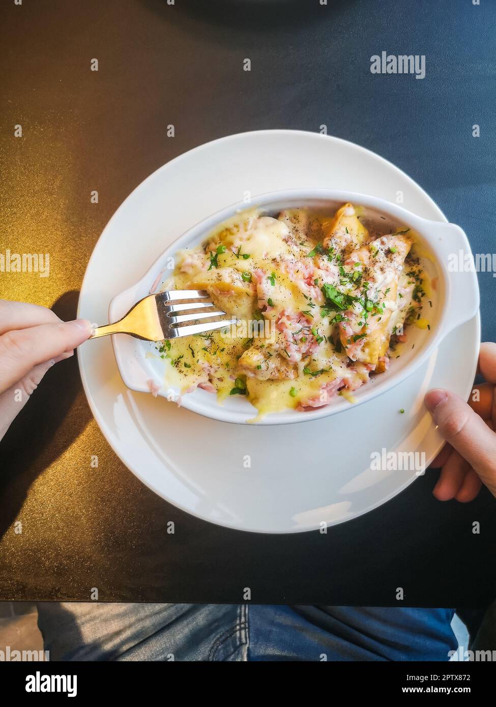 A man eats baked dumplings with a sauce of bacon, ham, herbs and cheese Stock Photo Alamy