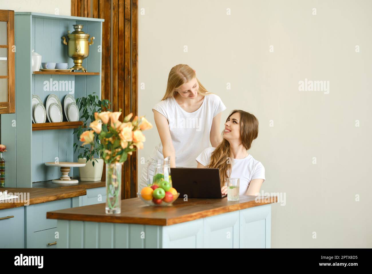 Two beautiful students making video conference call sitting in the kitchen Stock Photo