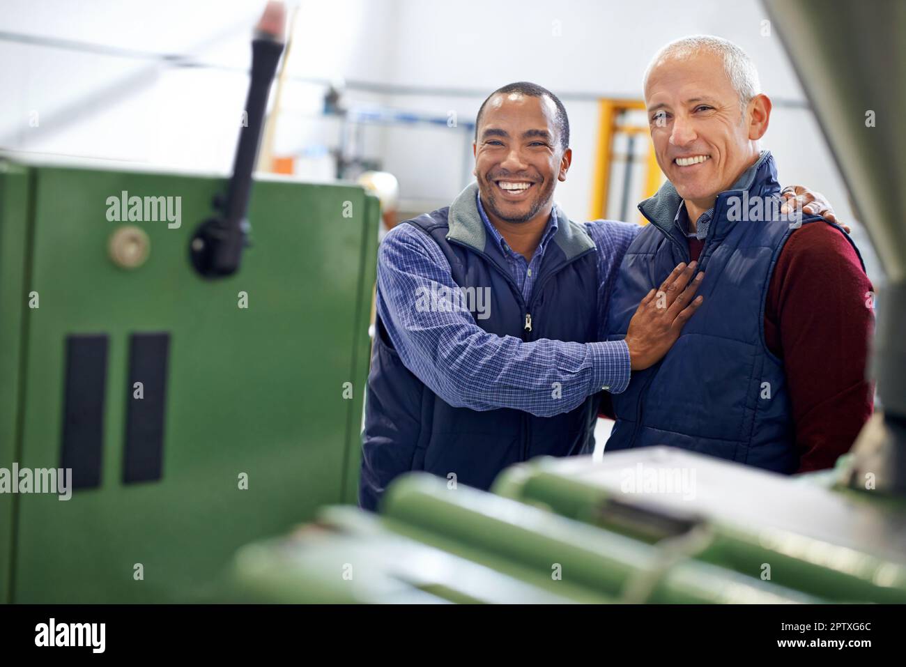 Its working like a charm. two men working over factory machinery Stock Photo