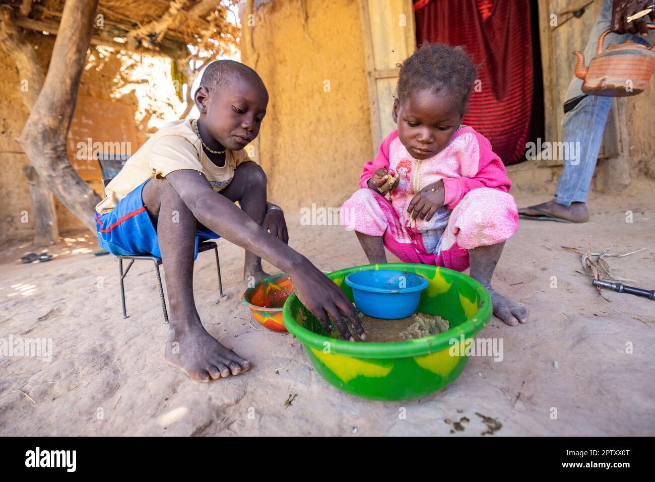 Children eat a communal meal of millet porridge paste and baobab leaf sauce in Segou Region, Mali, West Africa. 2022 Mali drought and hunger crisis. Stock Photo