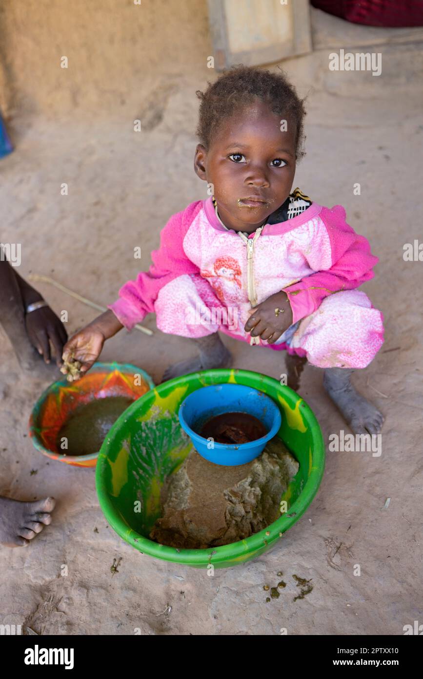 Children eat a communal meal of millet porridge paste and baobab leaf sauce in Segou Region, Mali, West Africa. 2022 Mali drought and hunger crisis. Stock Photo