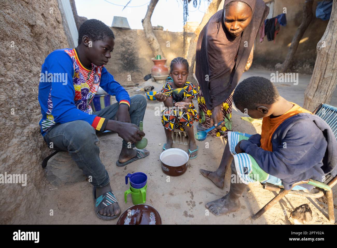A mother serves her children tea and porridge for breakfast in rural Segou Region, Mali, West Africa. 2022 Mali drought and hunger crisis. Stock Photo