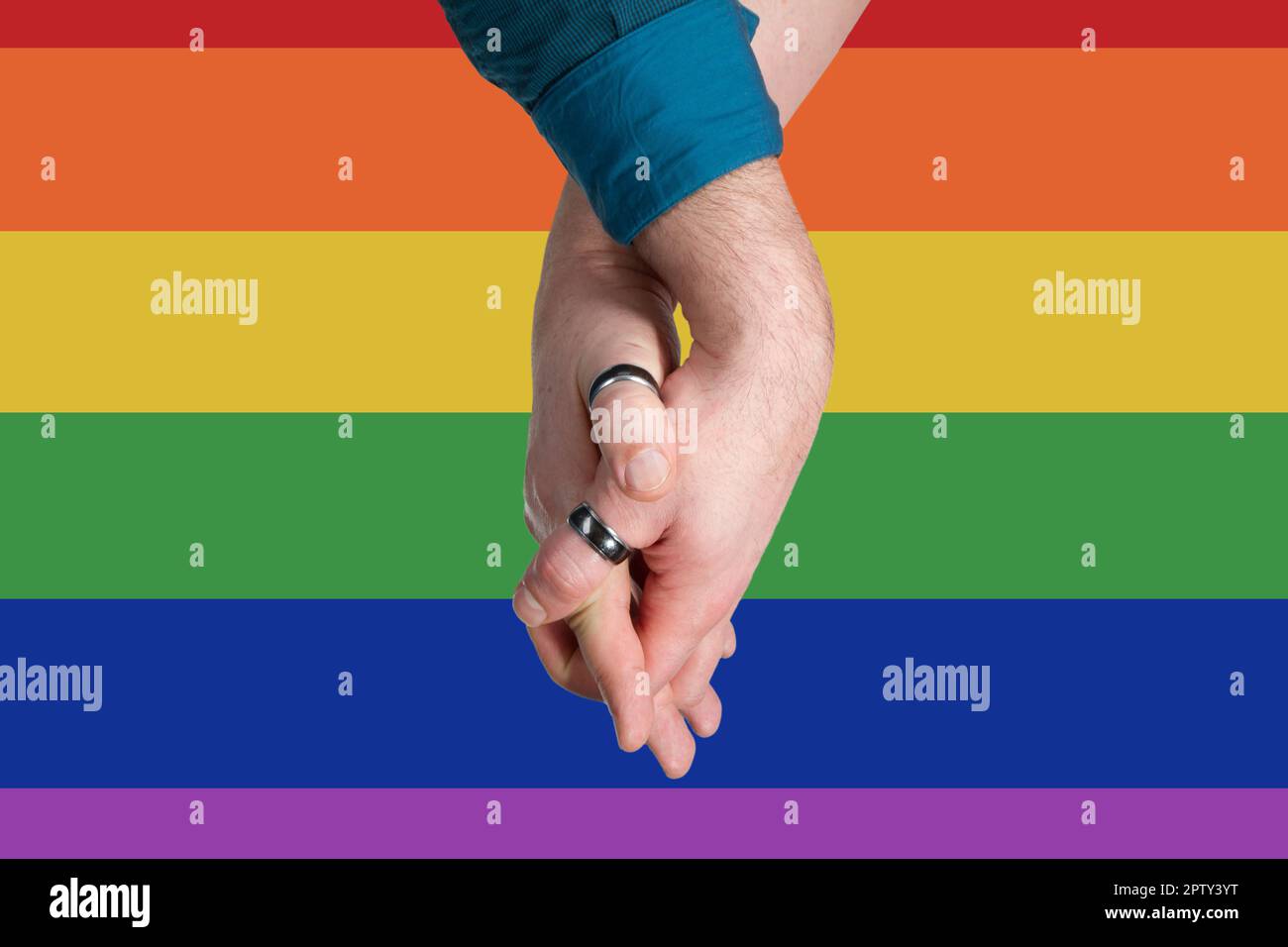 Homosexual couple hands into each other on rainbow flag background Stock Photo