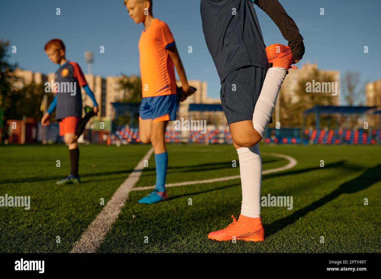 Young football players doing warm up workout stretching legs at soccer