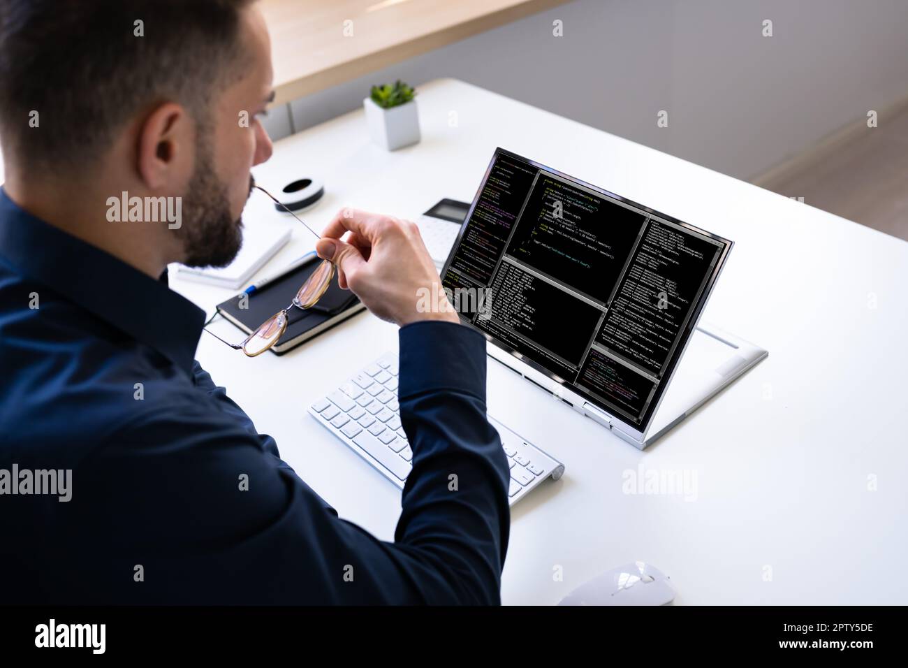 Programmer Or Coder At Office Desk Using Laptop Stock Photo