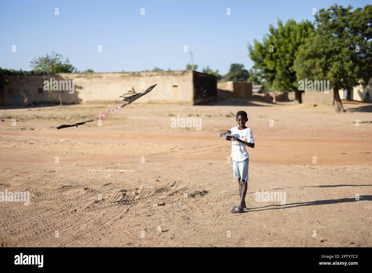 A young boy flies a homemade kite, made from plastic bags, in Segou Region, Mali, West Africa. 2022 Mali drought and hunger crisis. Stock Photo
