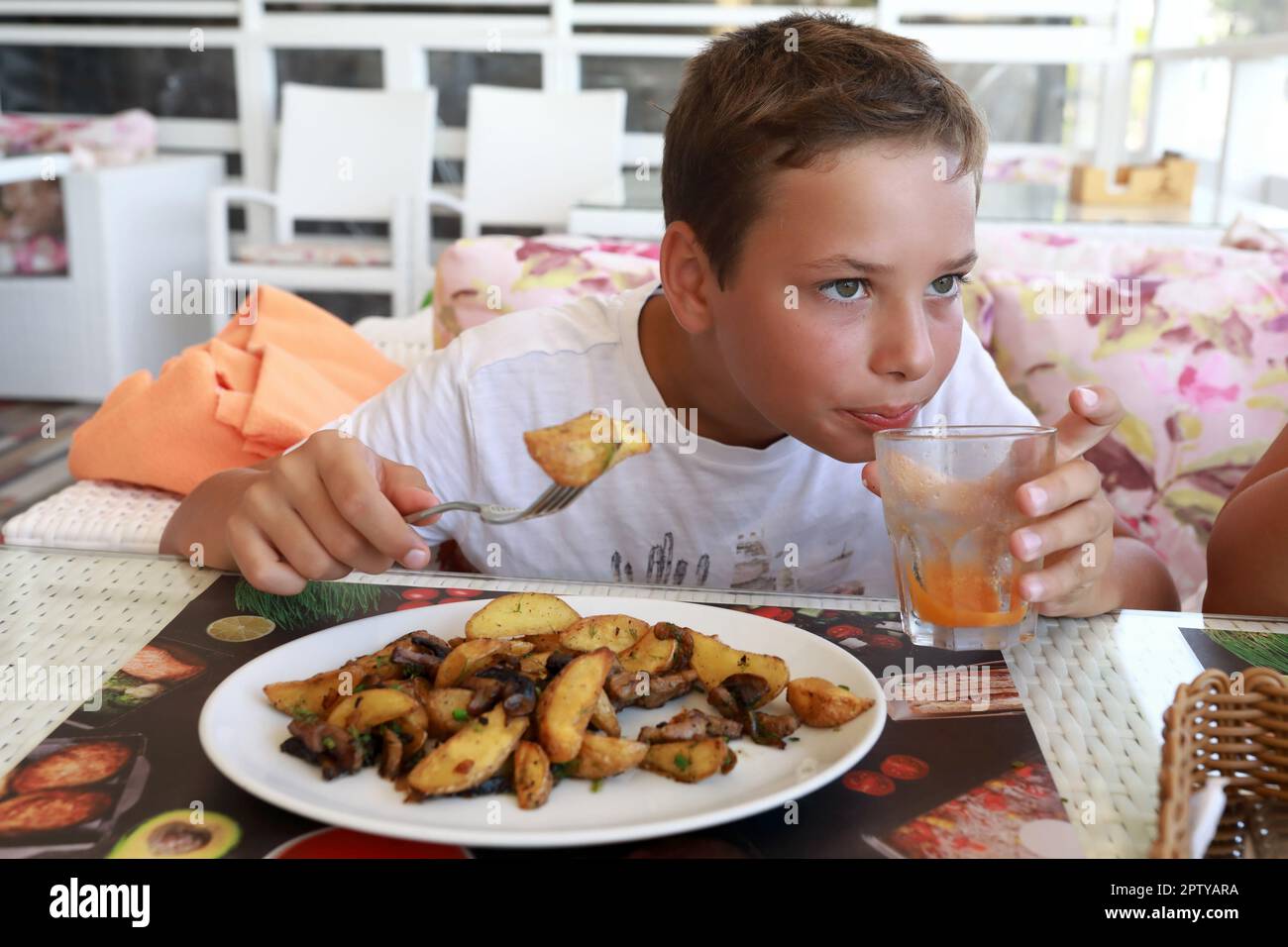 Child eating fried potatoes with mushrooms in restaurant Stock Photo