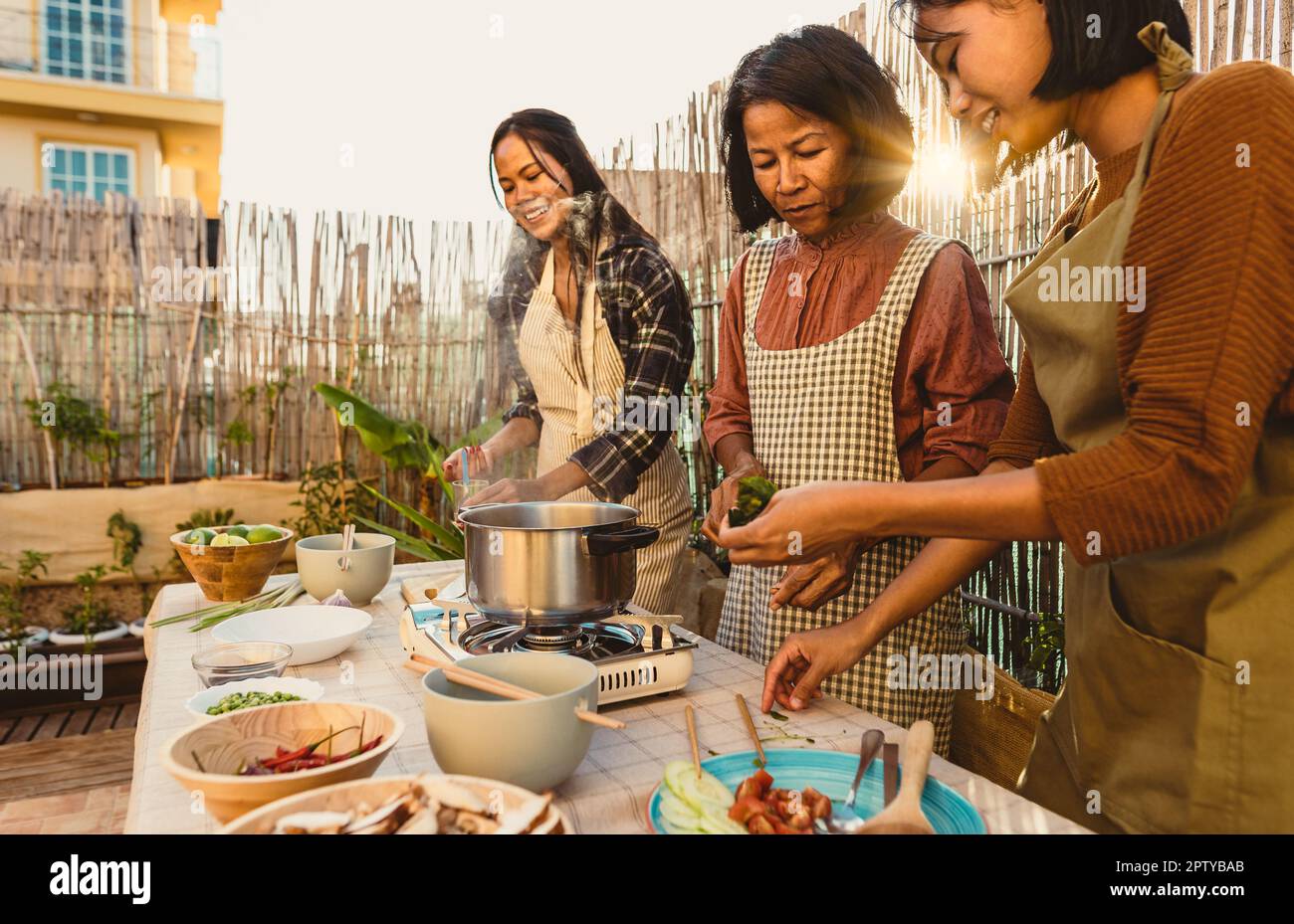 Southeast asian mother with her daughters having fun preparing food recipe together at house patio Stock Photo