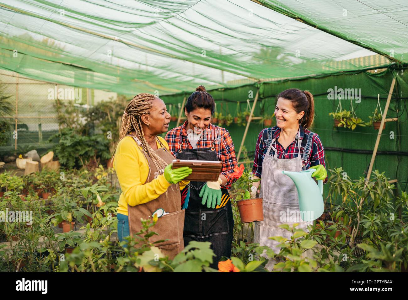 Happy multiracial women working together in plants and flowers garden shop Stock Photo